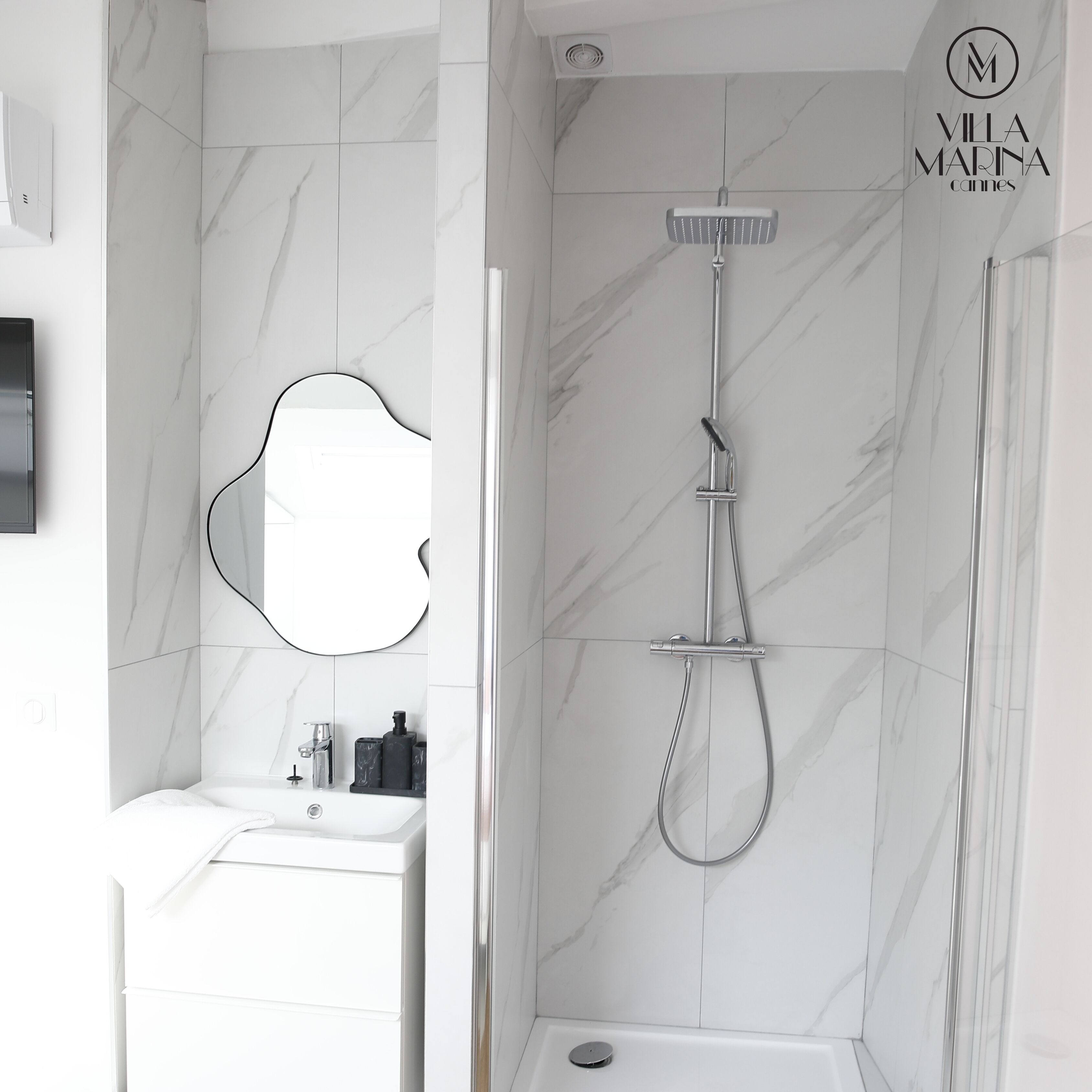 A modern bathroom with a shower, a sink, and a mirror.