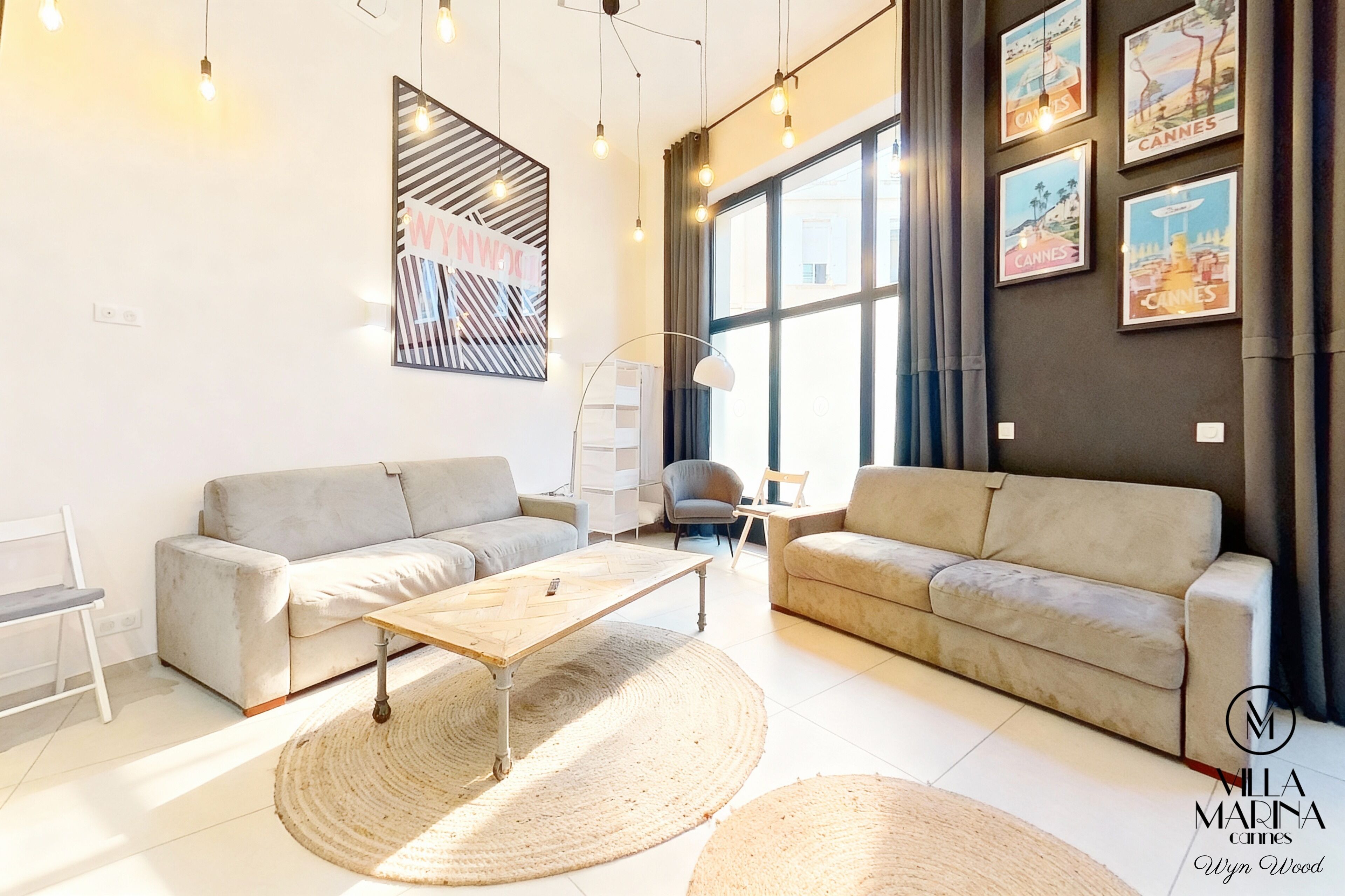 A modern living room with two sofas, a wooden coffee table, and a large window with curtains.