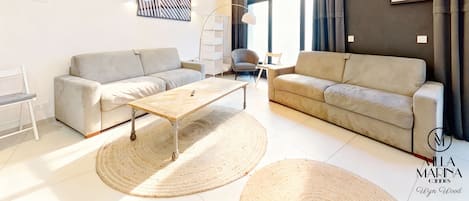 Un salon moderne avec deux canapés, une table basse en bois et une grande fenêtre agrémentée de rideaux.