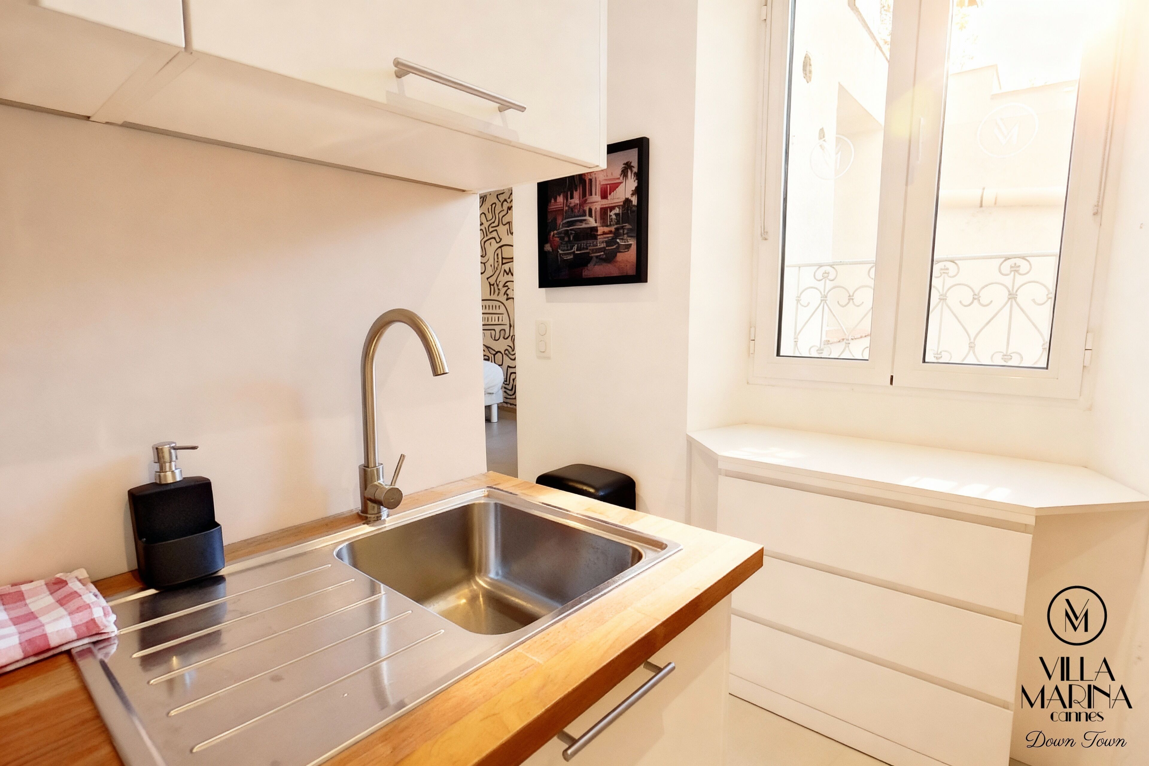 Una cocina moderna con un lavamanos de acero inoxidable, encimera de madera y ventana con vistas al balcón.
