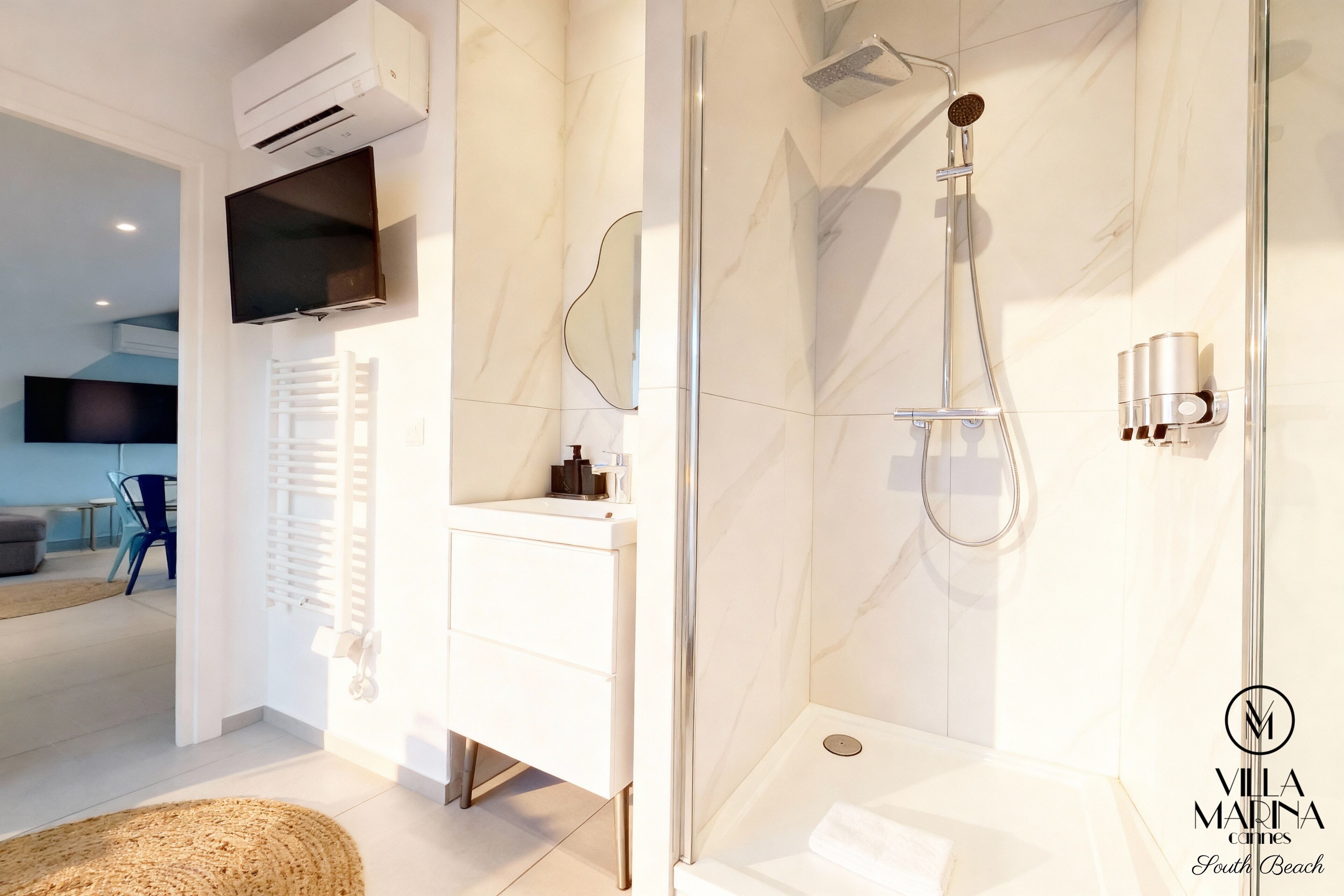 A modern bathroom with a glass-enclosed shower, a white vanity, and a mounted TV.