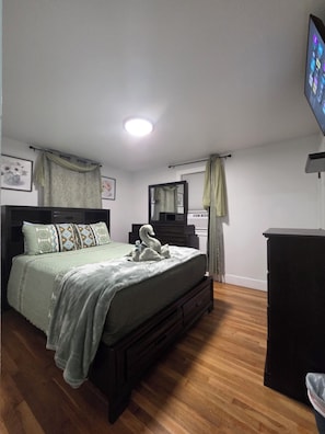 Ein Schlafzimmer mit einem Bett, einem Schminktisch, einem Spiegel und einem Fernseher an der Wand.