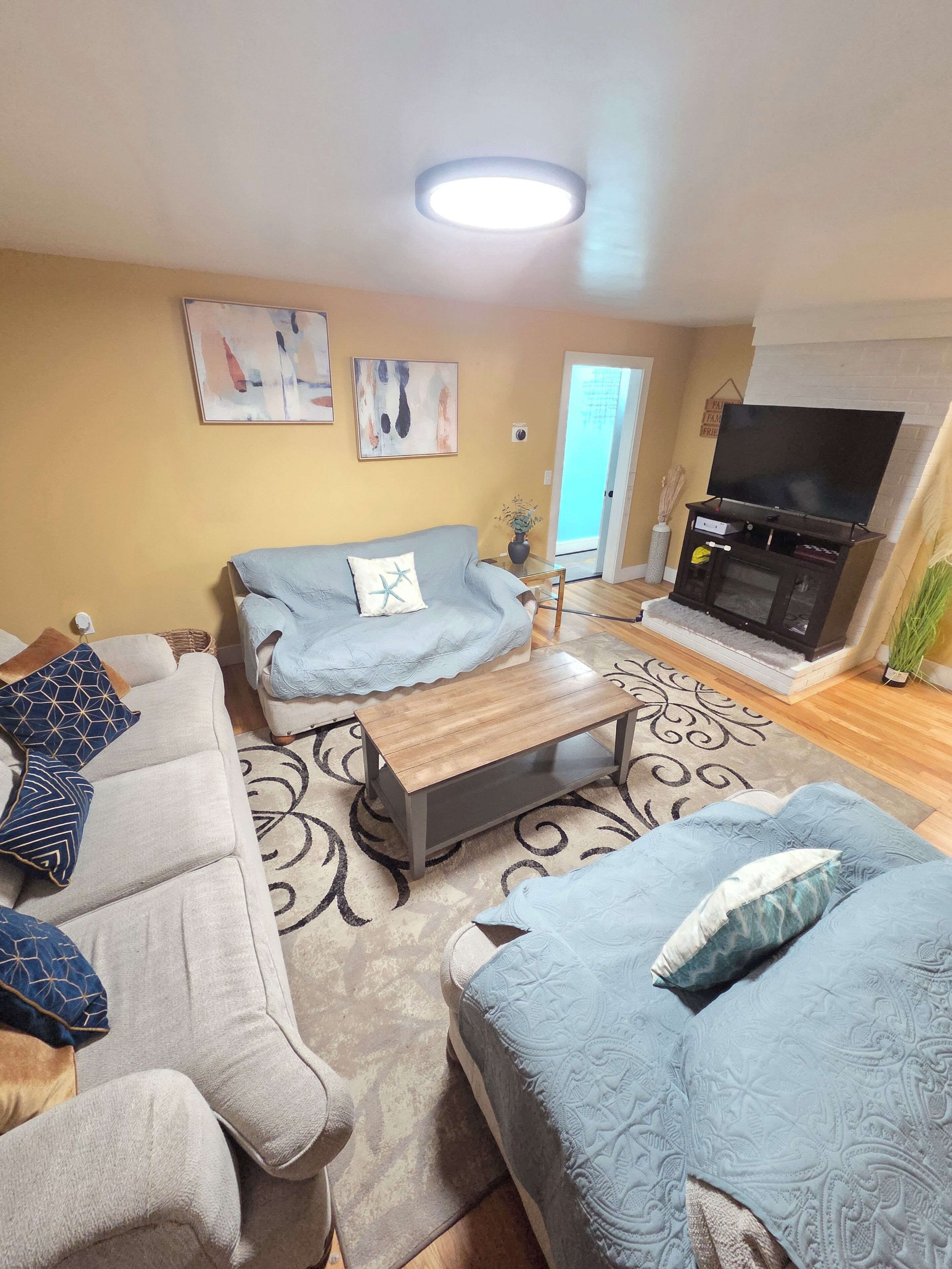 A living room with a sofa, a coffee table, a TV, and artwork on the wall.