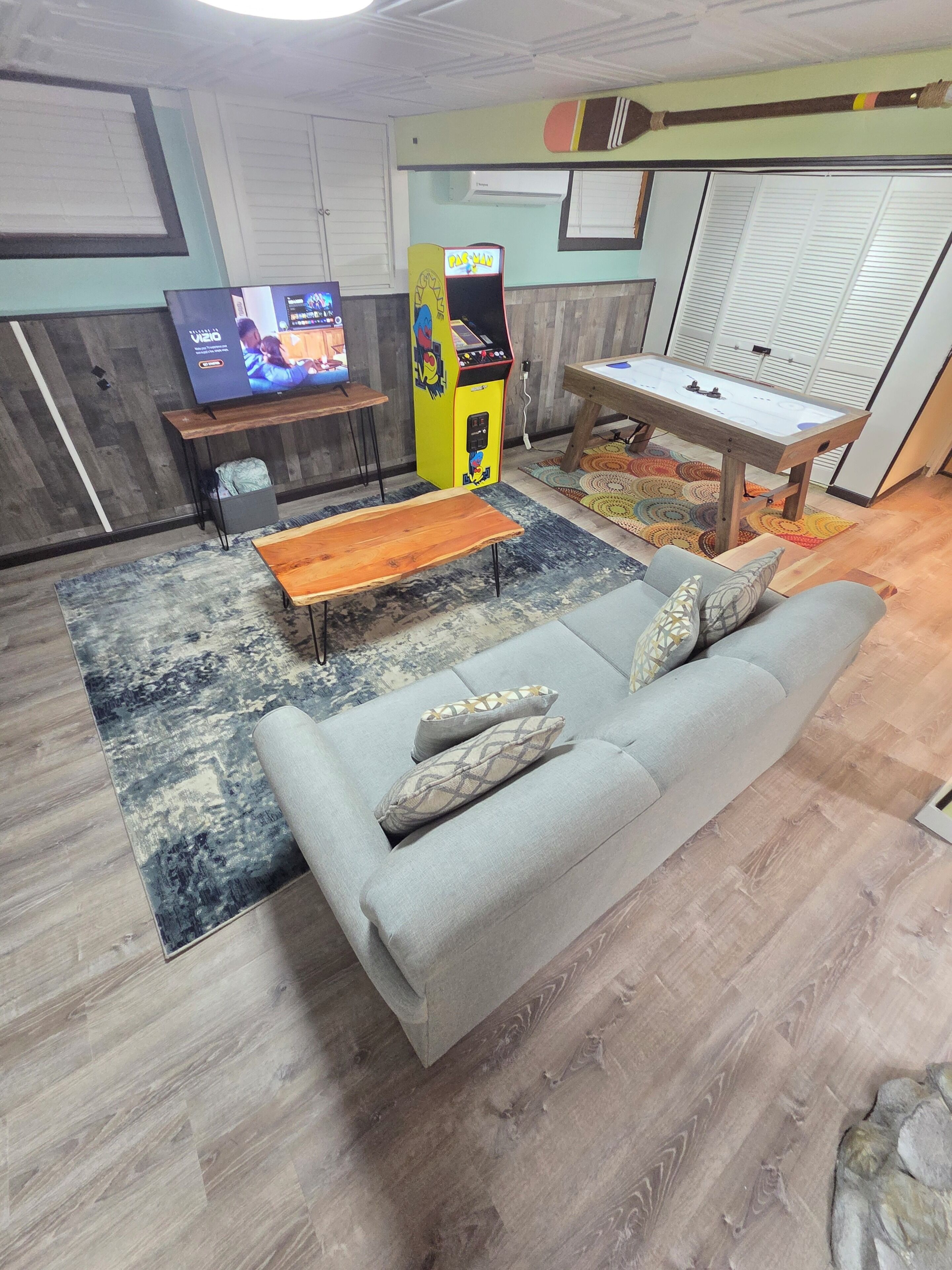A living room with a grey sofa, a wooden coffee table, a television, and a video game console.
