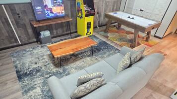 A living room with a grey sofa, a wooden coffee table, a television, and a video game console.