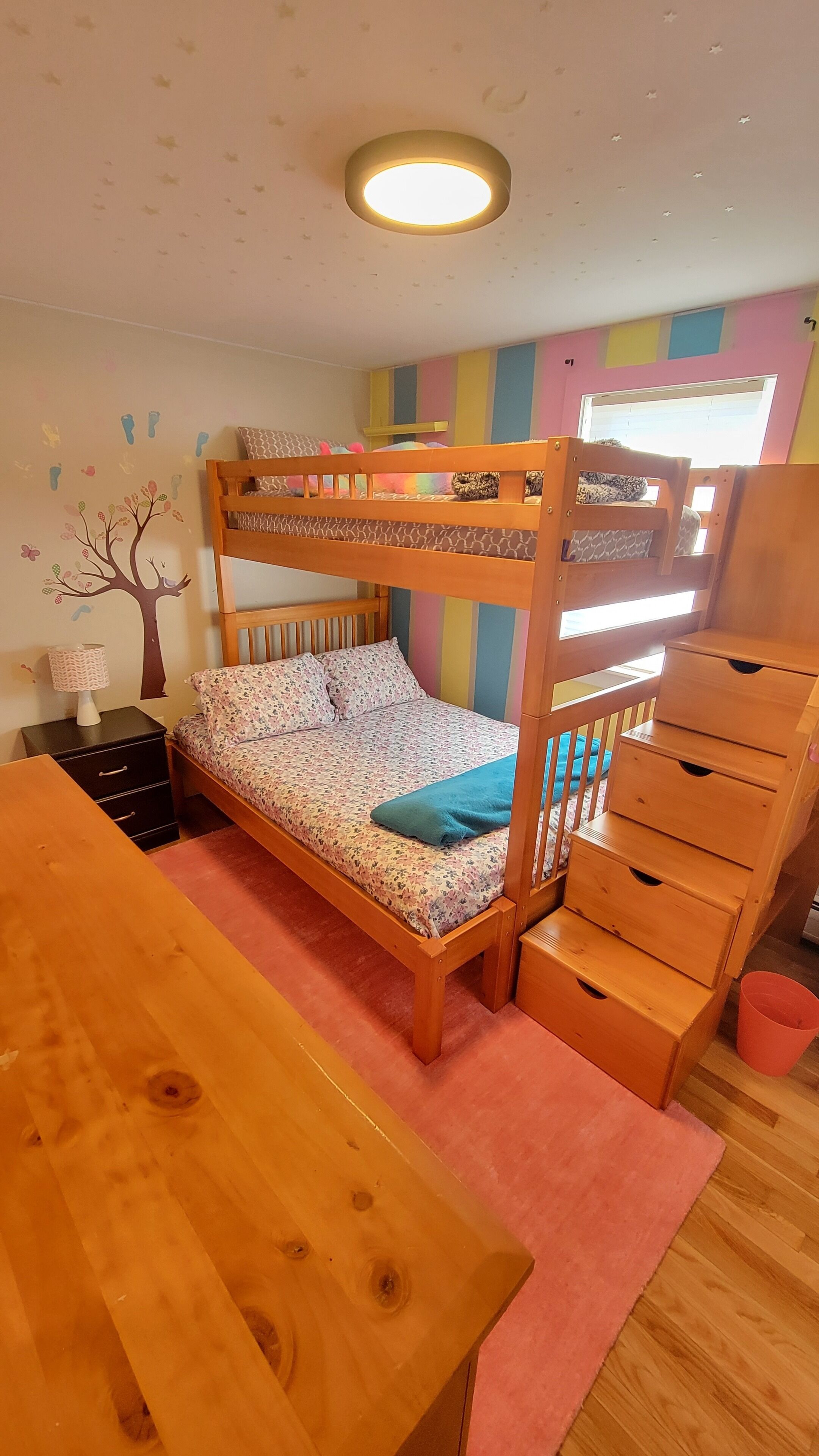 Ein Schlafzimmer mit Etagenbett, einem Holztisch, einer Kommode und einer Wandsticker.