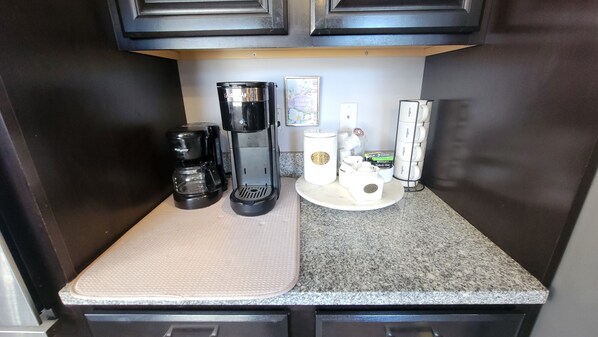Eine Küche mit Kaffeemaschine, Kaffeekanne und Kaffeeautomaten auf der Arbeitsfläche.