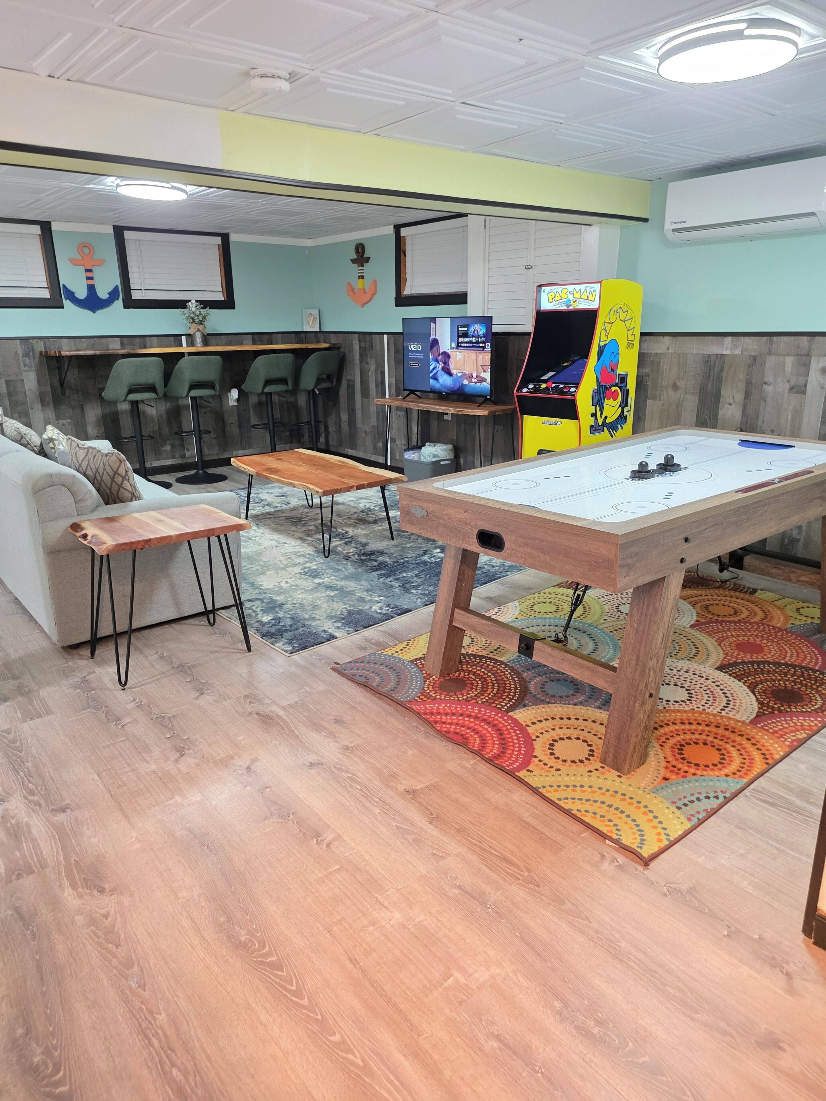 Une pièce équipée d’un baby-foot, d’un canapé, d’une télévision et d’un coin bar.