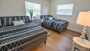 A bedroom with two beds, a ceiling fan, and two windows with blinds. - Large & Comfy Beach Apartment with Screened Patio (West Palm Beach)