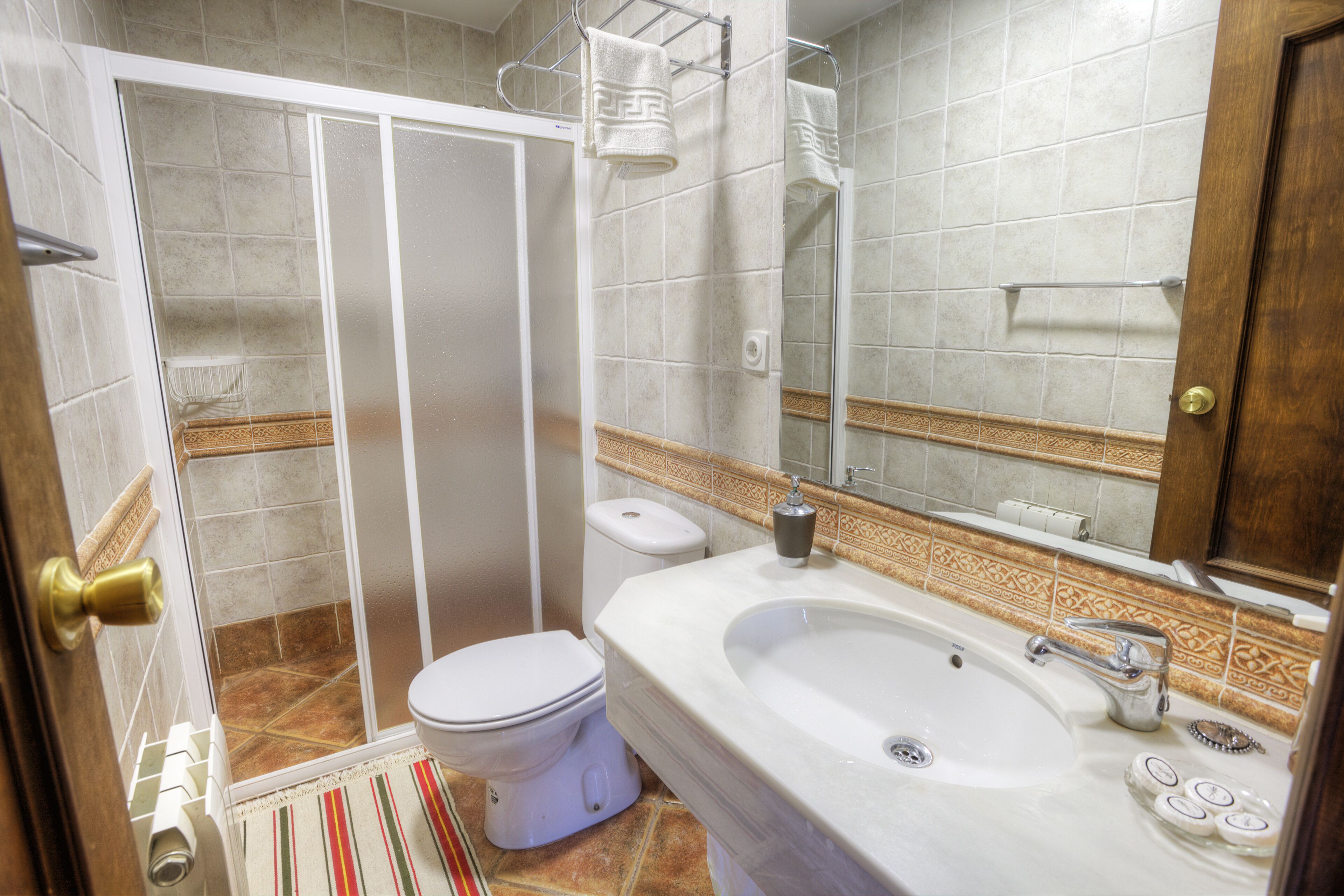 Ein Badezimmer mit Dusche, Toilette, Waschbecken und Spiegel.