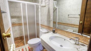 Ein Badezimmer mit Dusche, Toilette, Waschbecken und Spiegel.