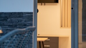 Moderni sisustus, jossa on yksi seinä koristeltu kivellä, ruokailutila pöytineen ja tuoleineen sekä suuri ikkuna, jossa on sälekaihtimet.
