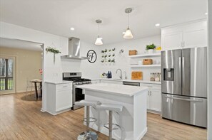 Enjoy cooking in this well-equipped kitchen with a central island, bar stools, and stainless steel appliances.