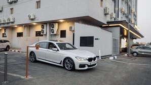 Un BMW blanco estacionado en un aparcamiento, con un edificio al fondo.