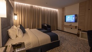 Una habitación de hotel con una cama grande, un televisor, un escritorio y una silla.
