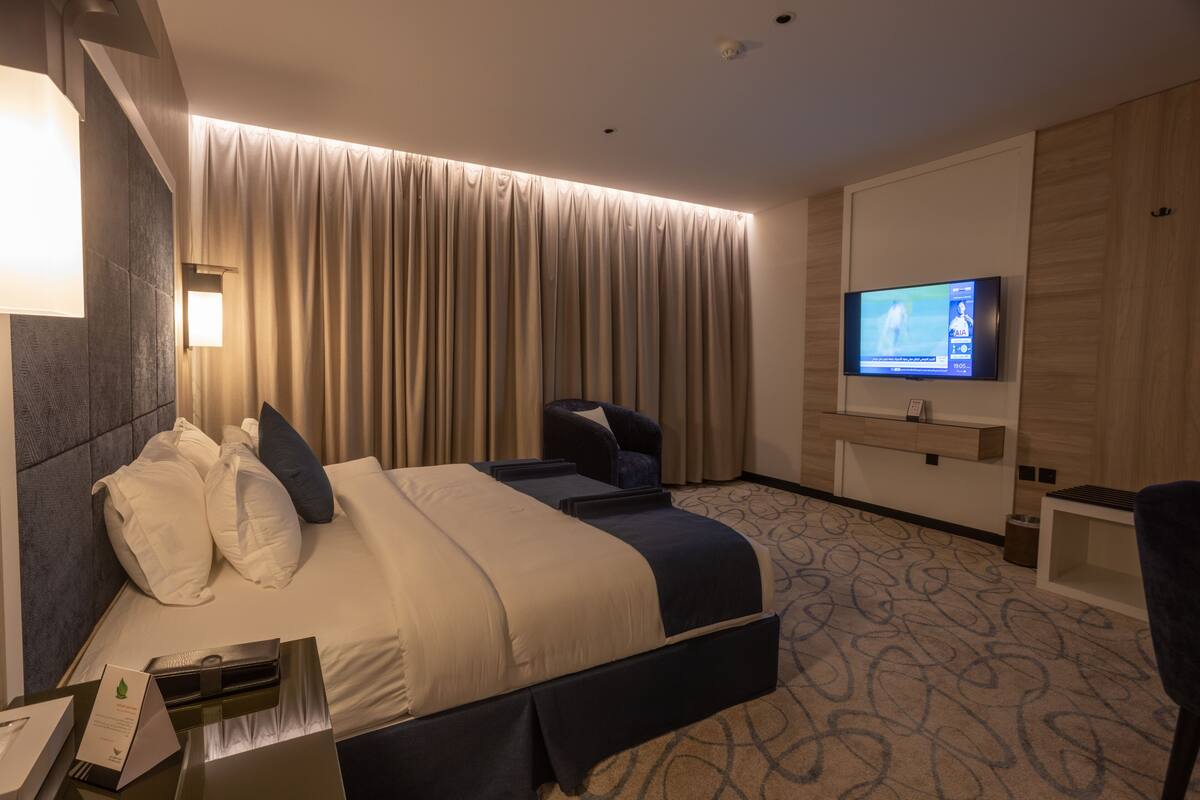 Ein Hotelzimmer mit einem großen Bett, einem Fernseher, einem Schreibtisch und einem Sessel.