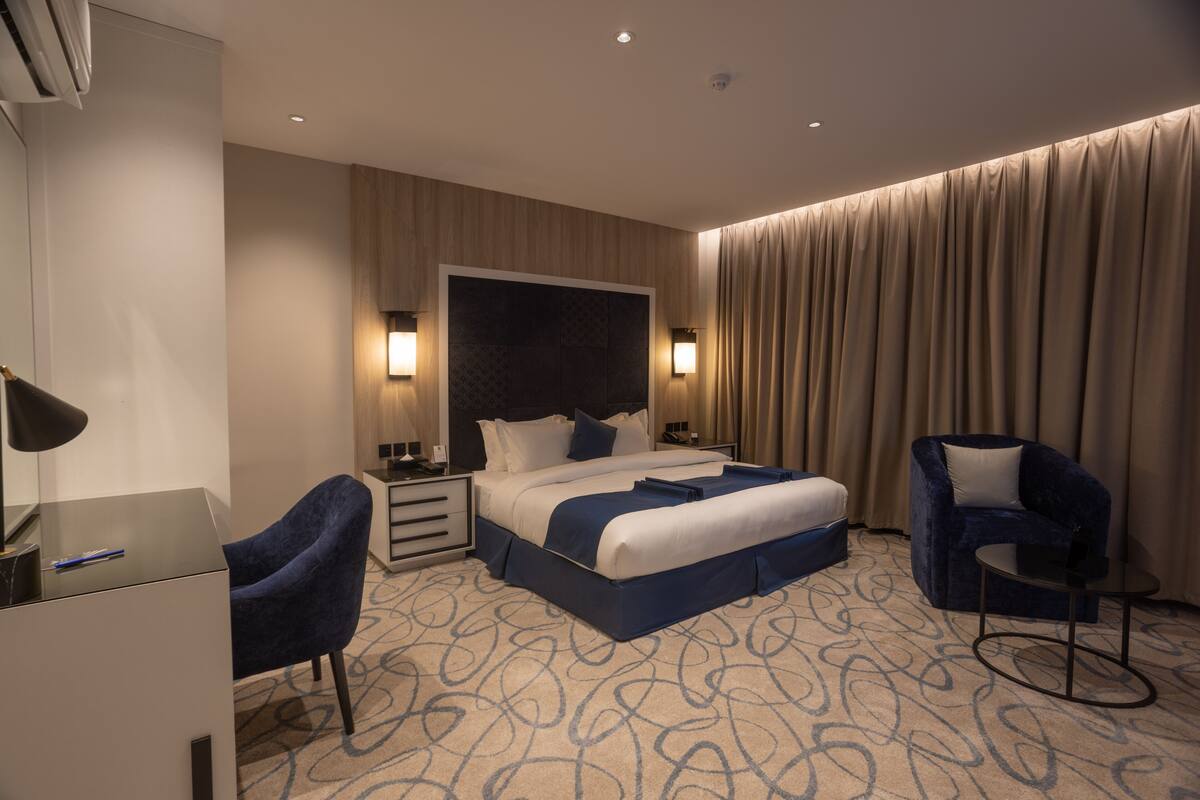 Ein Hotelzimmer mit einem großen Bett, zwei Stühlen, einem Schreibtisch und einem kleinen Tisch.
