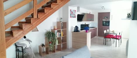 A modern kitchen with wooden cabinets, a built-in oven, and a dining area with a table and chairs.