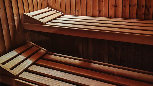 Eine Sauna mit Holzbänken und schrägverdeckter Decke.