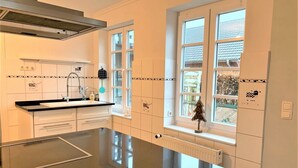 Eine moderne Küche mit einer großen Kochinsel, weißen Schränken und einem Fenster mit Blick nach draußen.