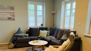 Ein Wohnzimmer mit Ecksofa, rundem Couchtisch und Schaukelstuhl.