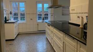 Eine moderne Küche mit weißen Schränken, einer schwarzen Arbeitsplatte und einem Fenster mit Blick auf einen Garten.
