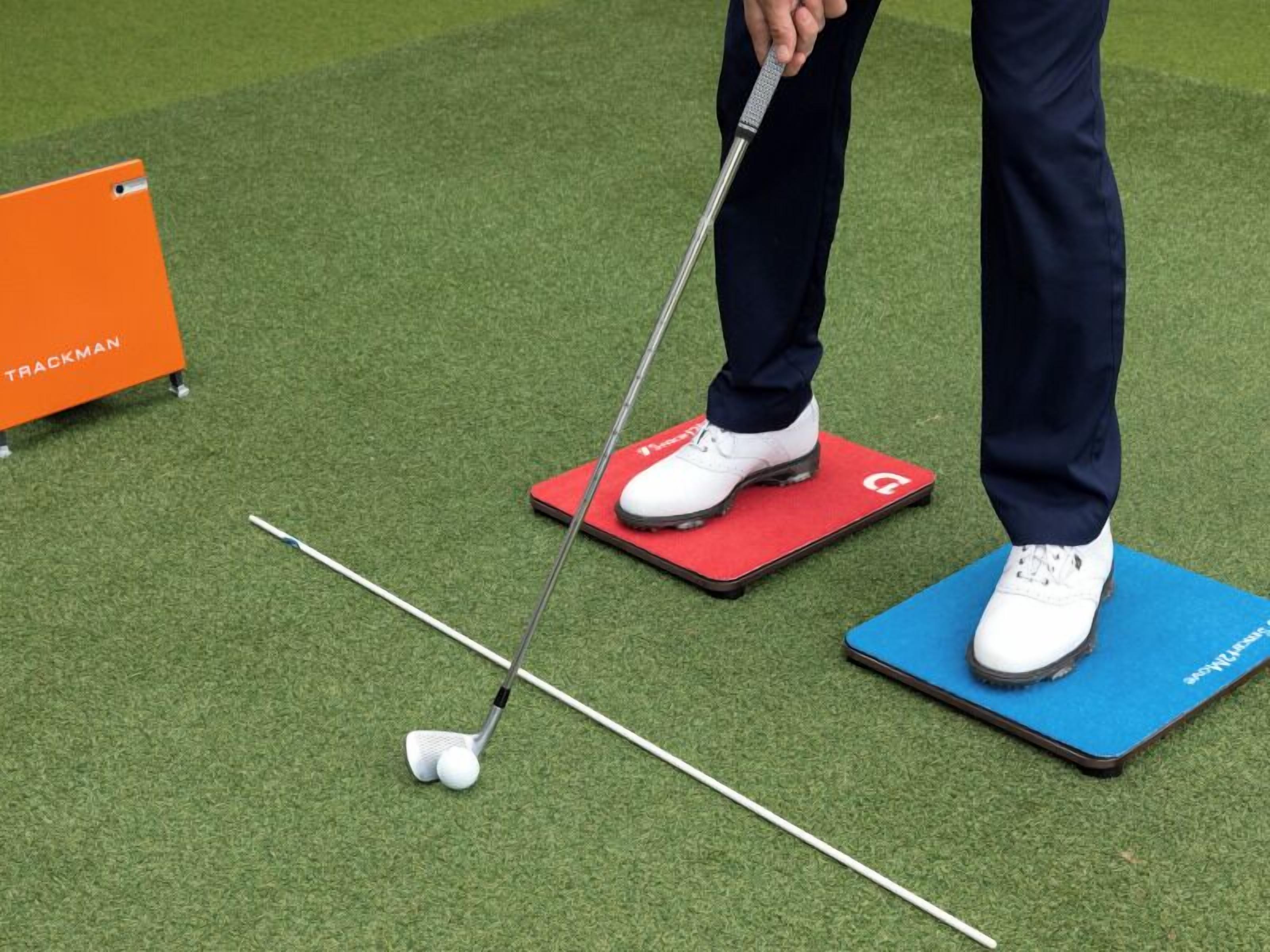 A golf course with a putting green, a red and blue mat, and a golf club.