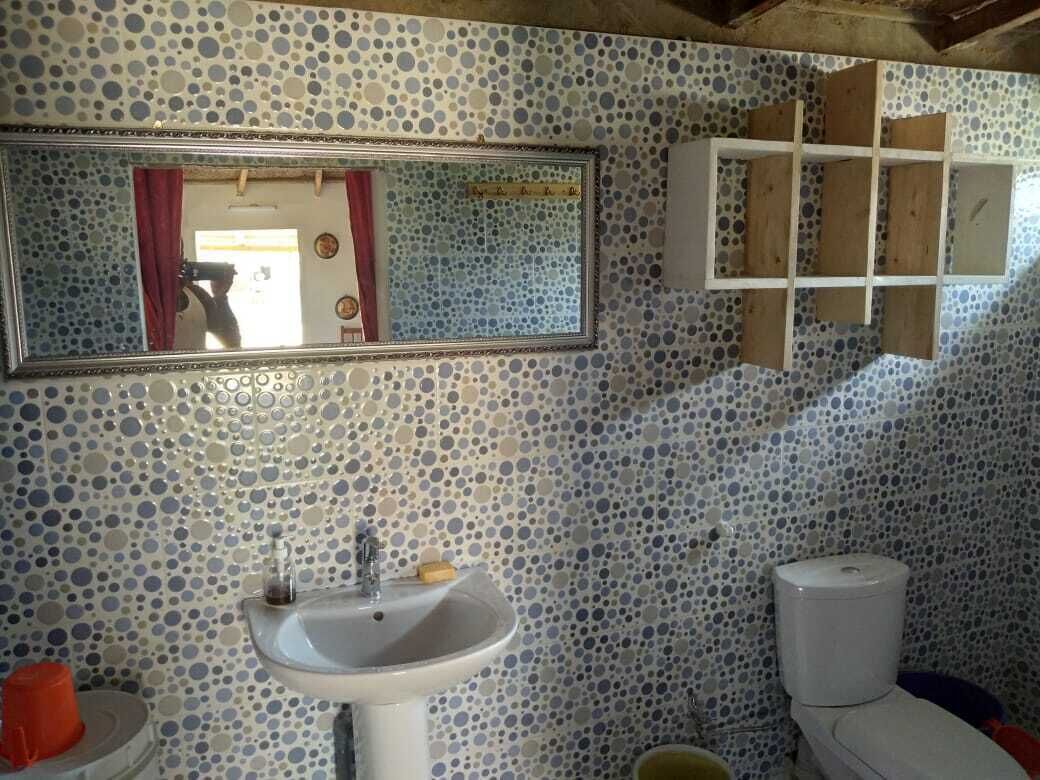 Une salle de bain avec un mur recouvert de mosaïques, un lavabo, un miroir et des toilettes.