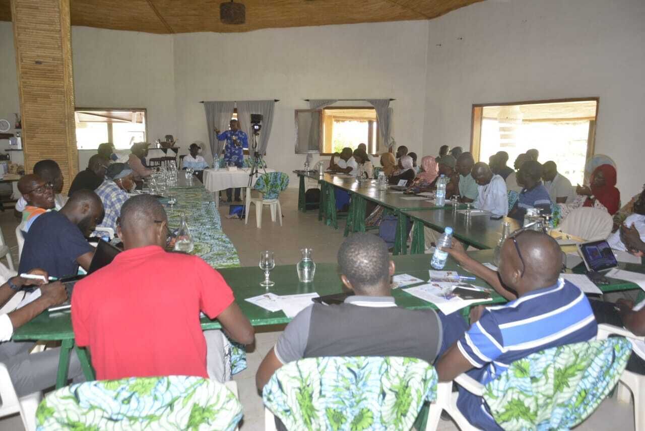 A conference room with a long table, chairs, and attendees.