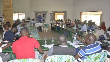 A conference room with a long table, chairs, and attendees.