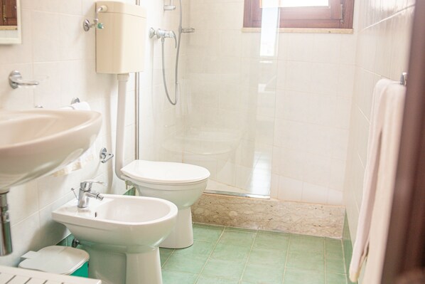 A bathroom with a sink, bidet, toilet, and shower. - hotel al paradise (San Vito Lo Capo)