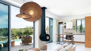 A modern kitchen with a large island, a dining area with bar stools, a built-in oven, and a large window overlooking a pool and greenery. - BRAND NEW Lux Villa*Private Heated SaltyPool*BBQ*SeaView (Daratsos)