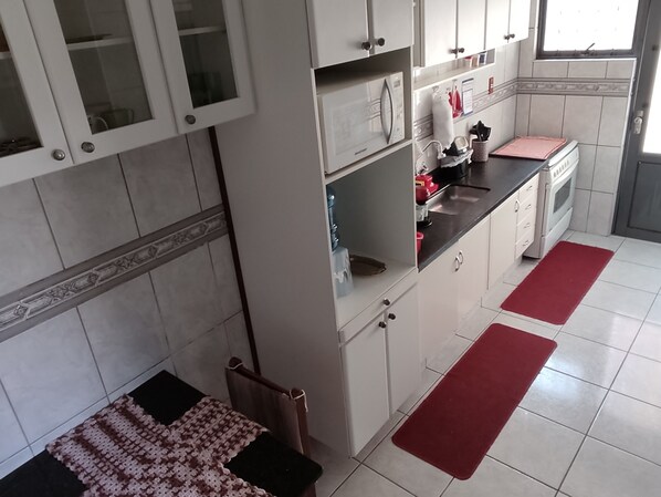 A kitchen with white cabinets, a black countertop, and red rugs.