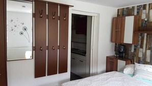 Une chambre comprenant un lit, une armoire, un miroir et un coin cuisine.