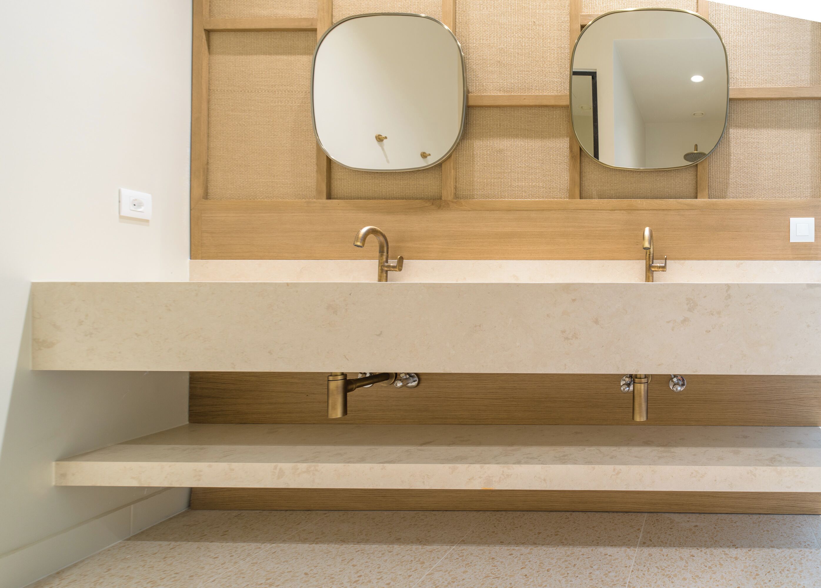 Un baño con tocador de madera, dos espejos y un lavabo.