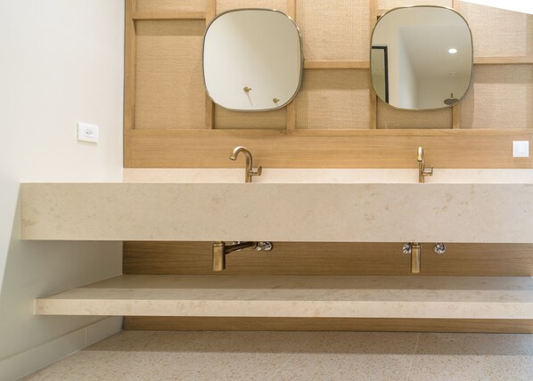 Un baño con tocador de madera, dos espejos y un lavabo.