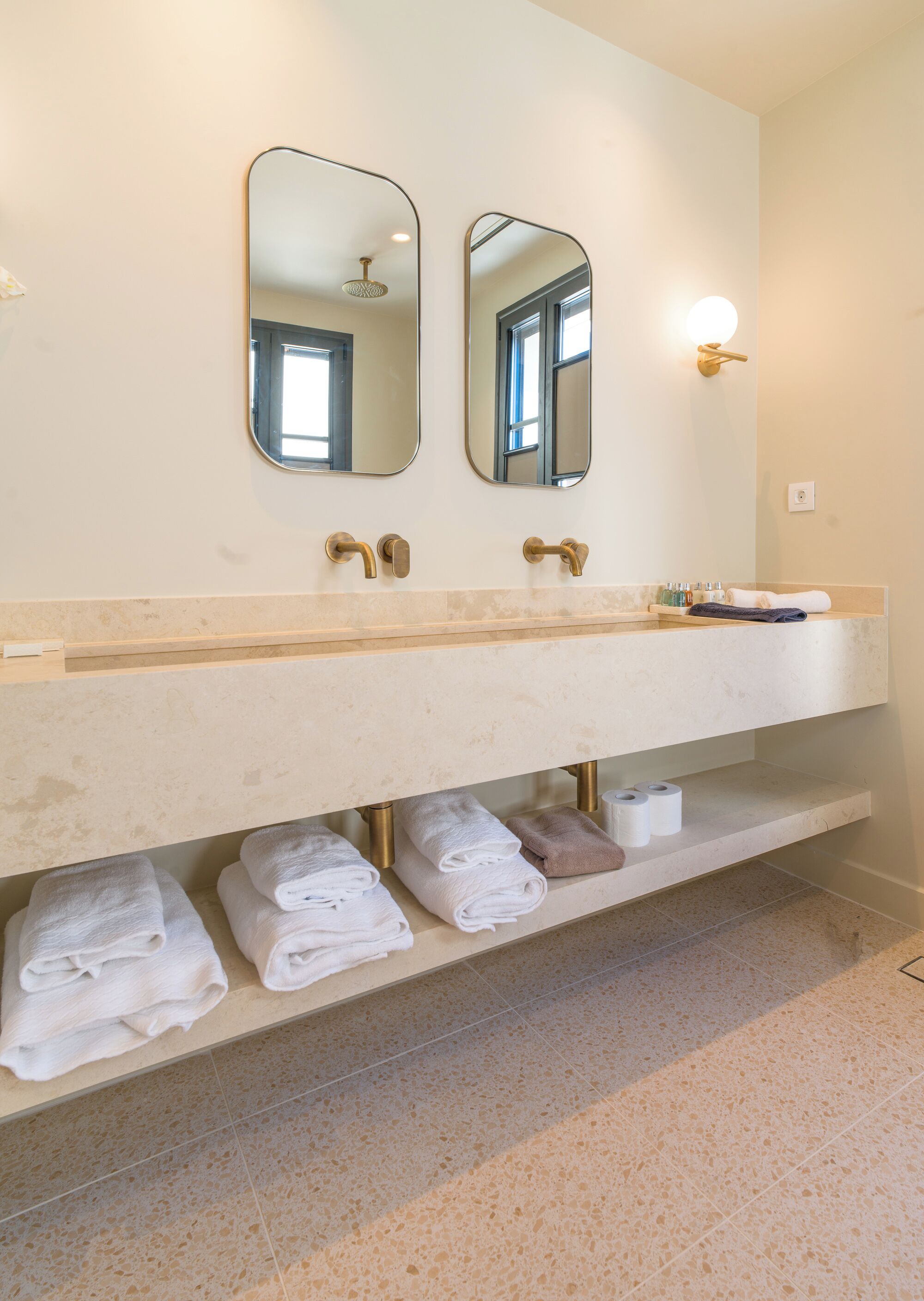A bathroom with a large mirror, two sinks, and a towel rack with neatly folded towels.