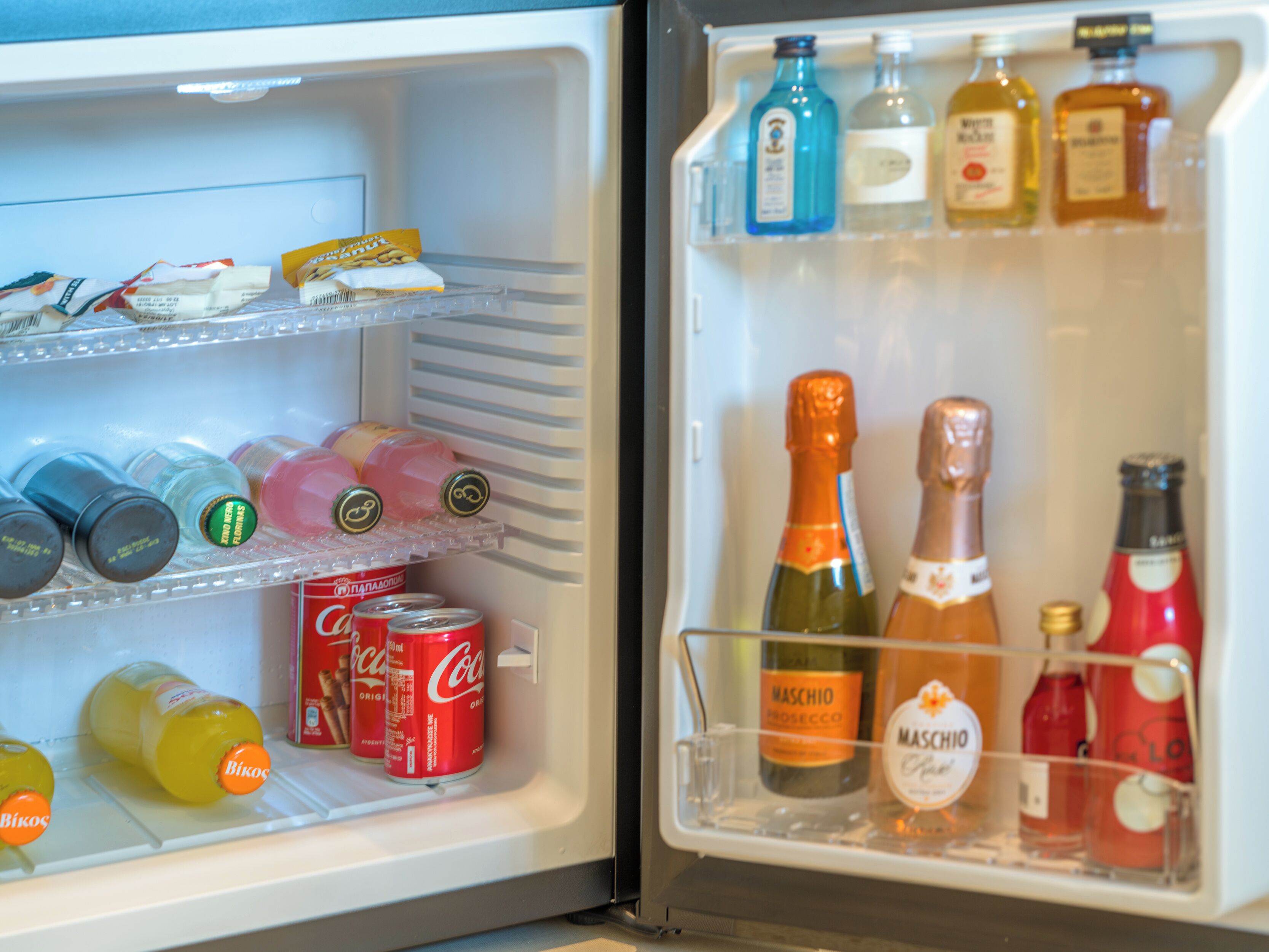 Un refrigerador abierto con diversas bebidas y aperitivos.