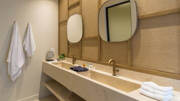 Un baño moderno con un lavamanos alargado, dos grifos, un espejo grande y un perchero para toallas.