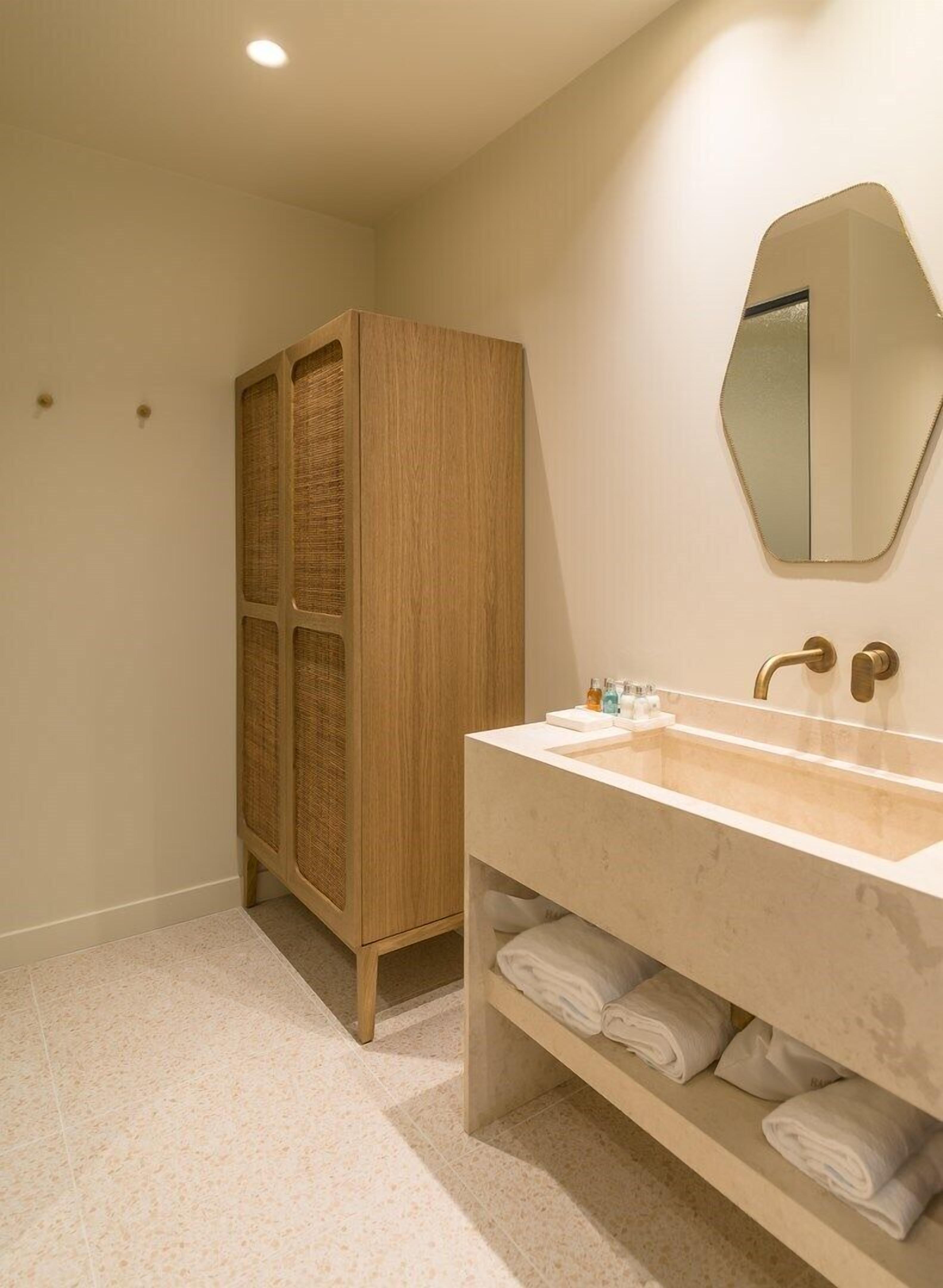A bathroom with a wooden cabinet, a large mirror, and a sink with towels.