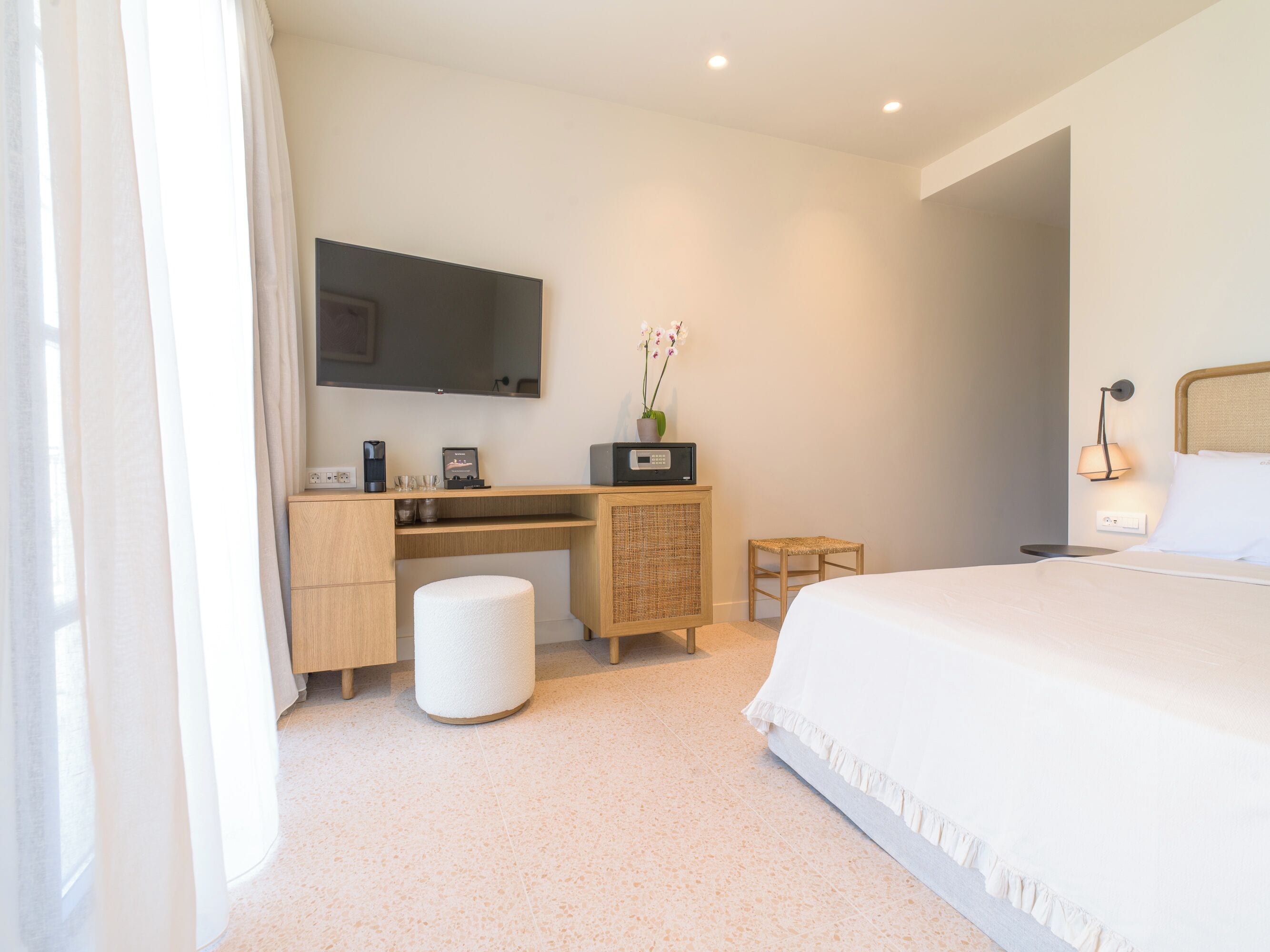 A modern hotel room with a bed, a desk, a chair, a toilet, and a large mirror.