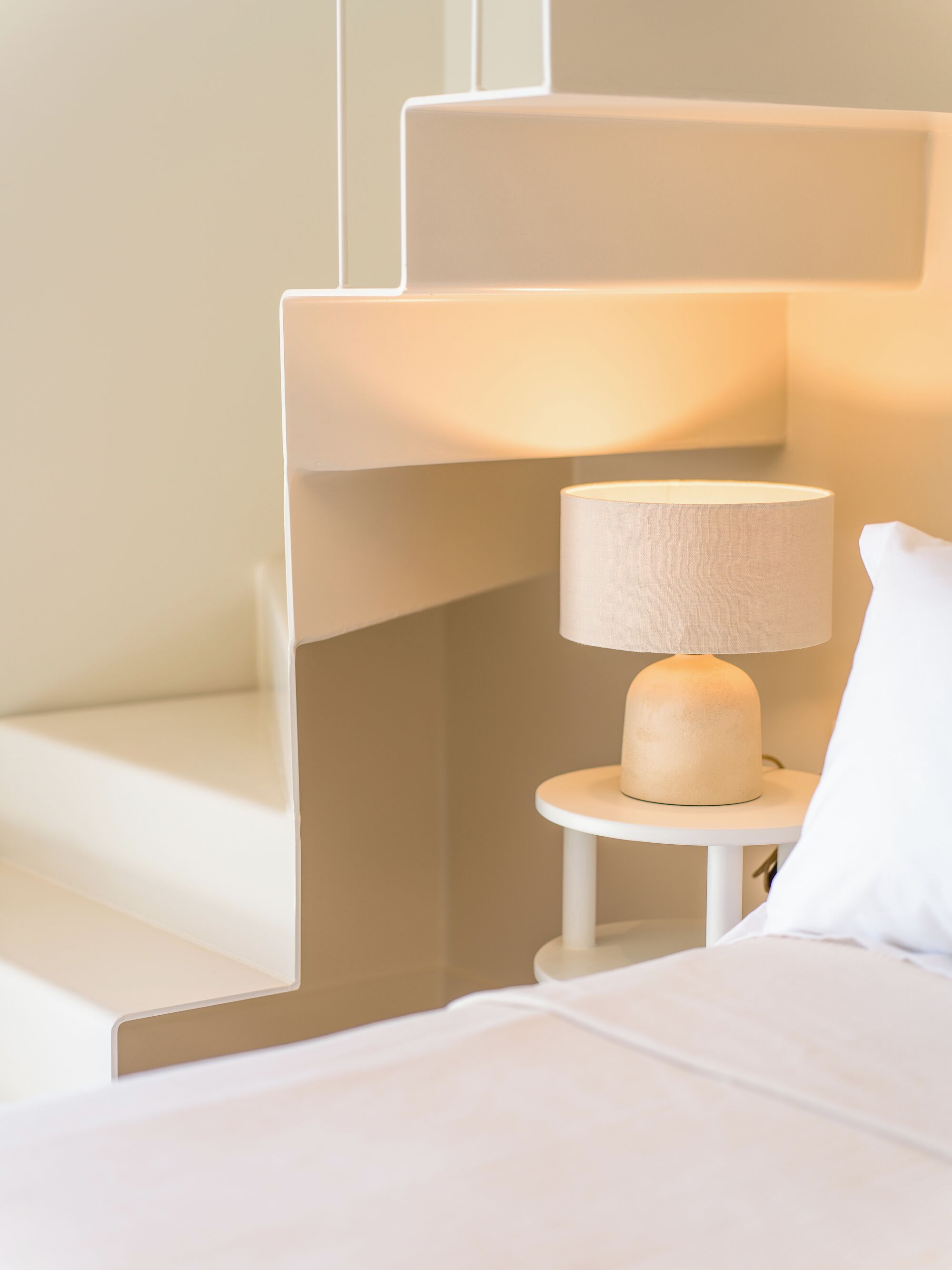A modern bedroom with a bed, a nightstand, and a lamp.