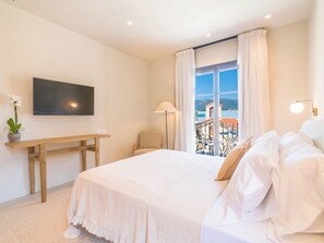 Ein Hotelzimmer mit Bett, Schreibtisch, Stuhl, Fernseher und einem Balkon mit Blick.