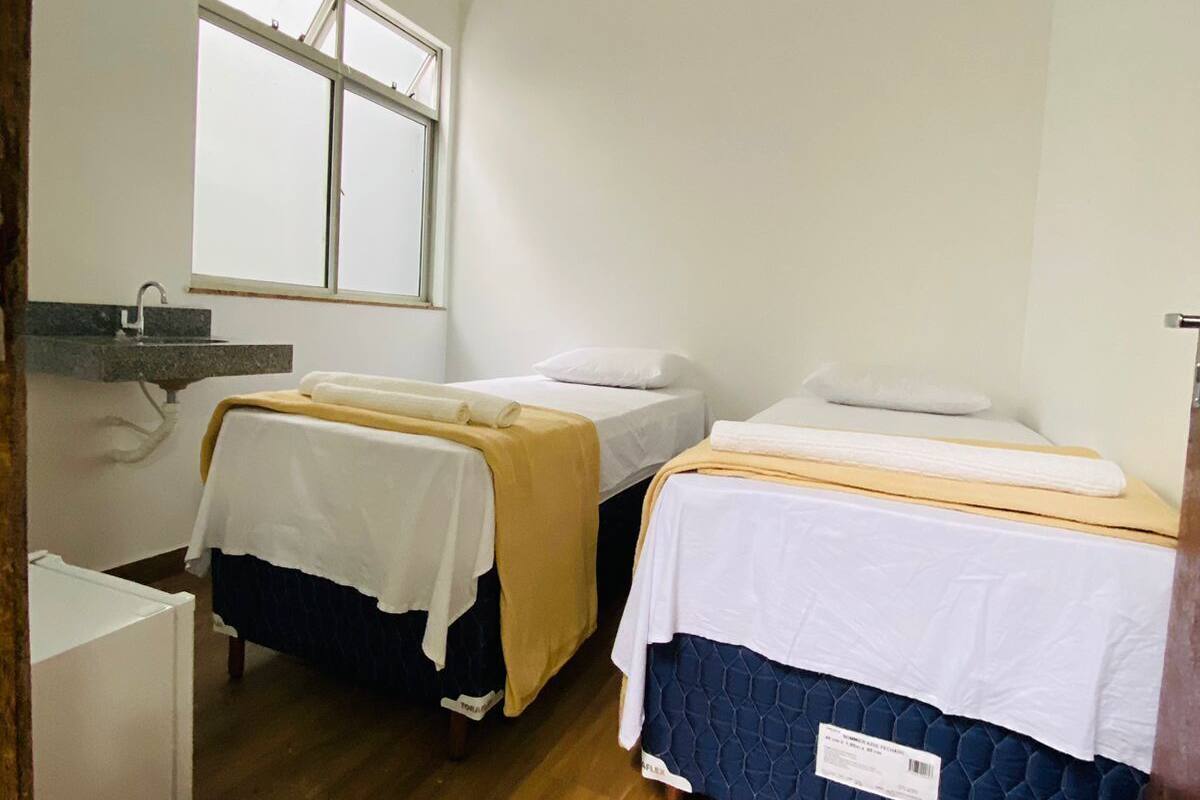 A small, clean room with two beds, a window, and a desk.