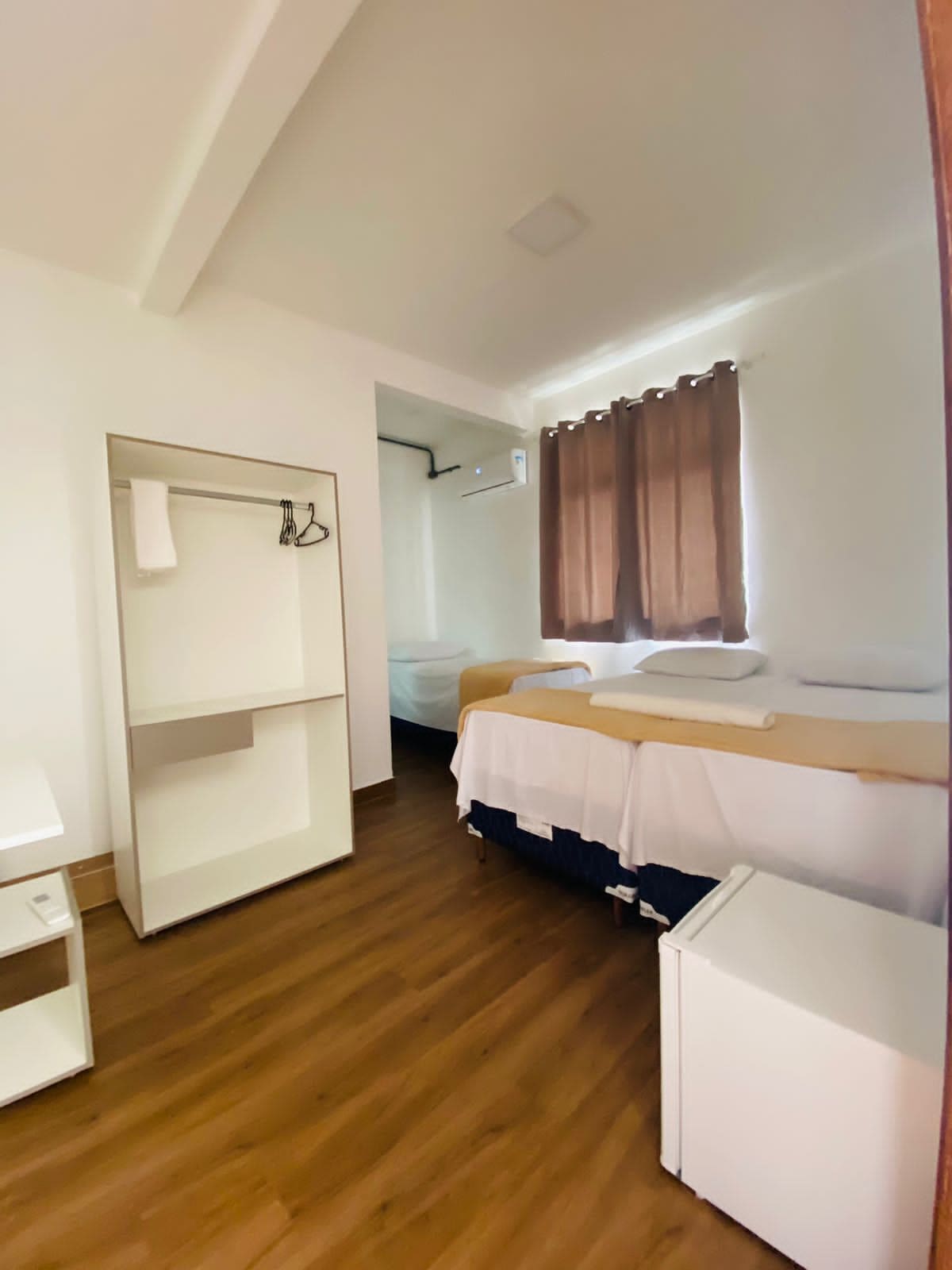 Un dormitorio con literas, un escritorio pequeño blanco, un armario y un baño visible a través de una puerta abierta.