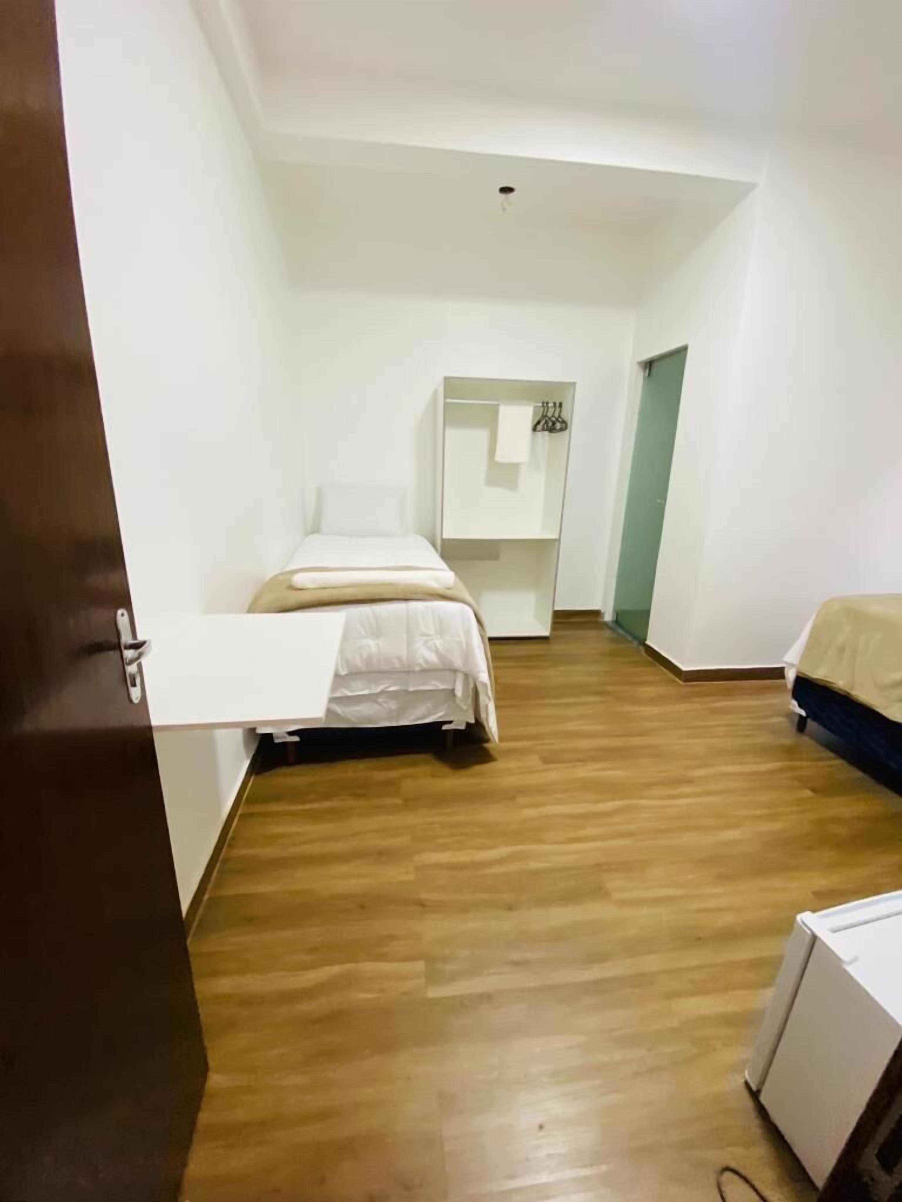 Una habitación de hotel con una cama, un escritorio pequeño y un armario.