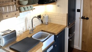 Une cuisine compacte dotée d’un plan de travail en bois, d’un four à micro-ondes encastré, d’un grille-pain et d’un évier.