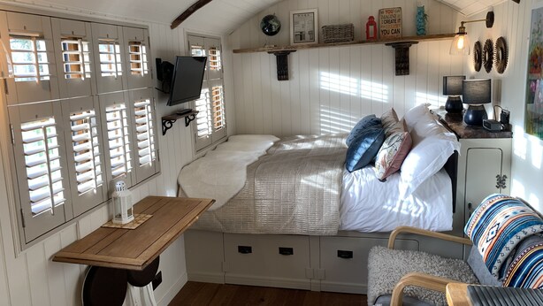 Une chambre confortable avec un lit, une petite table, une chaise et un téléviseur fixé au mur.