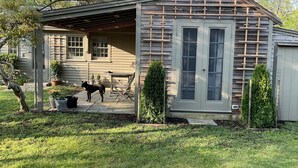 A wooden house with a covered porch, a fenced yard, and a dog standing outside. - Barn/cottage (Nantucket)