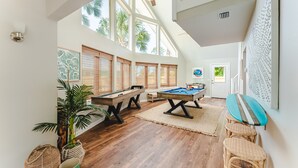 A spacious room with a pool table, another pool table, and a surfboard against the wall. - Heated Pool • Sauna • Hot Tub • Game Room • Beach • Golf Cart • Sleeps 15 (Port St. Joe)